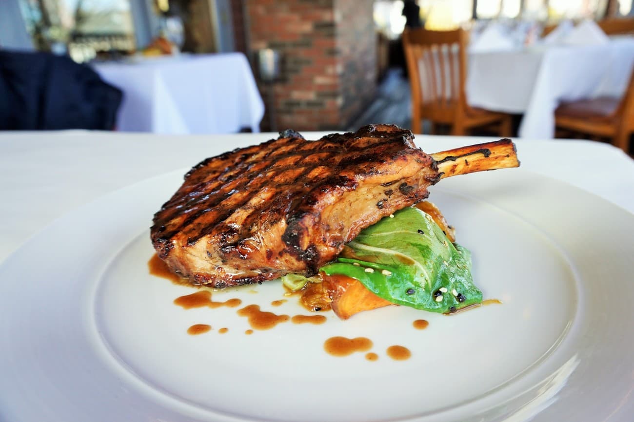 Grilled bone-in pork chop with braised greens and roasted sweet potato